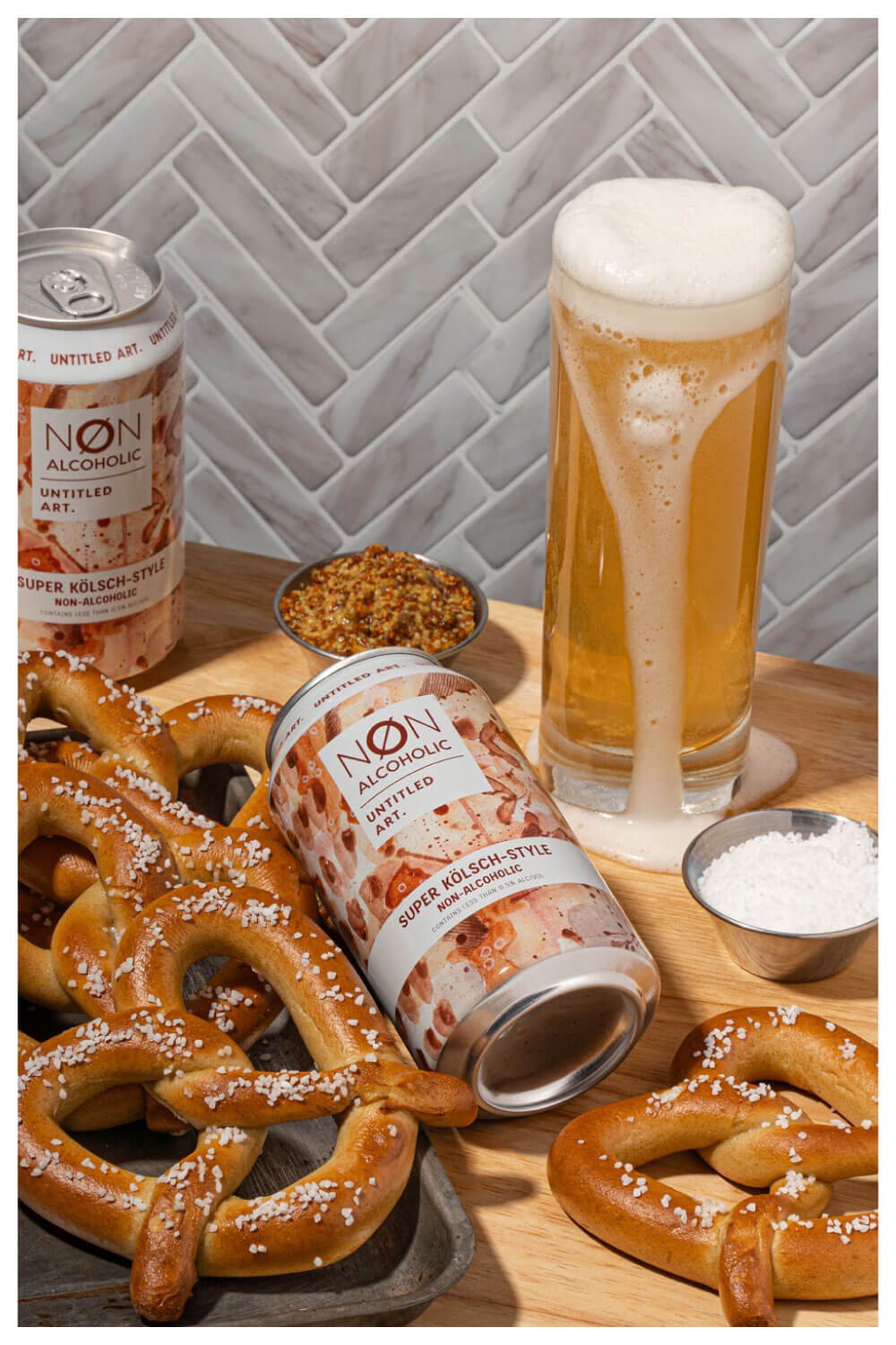 Untitled Art Non-alcoholic Super Kolsch-style beer in a glass and cans with soft pretzels